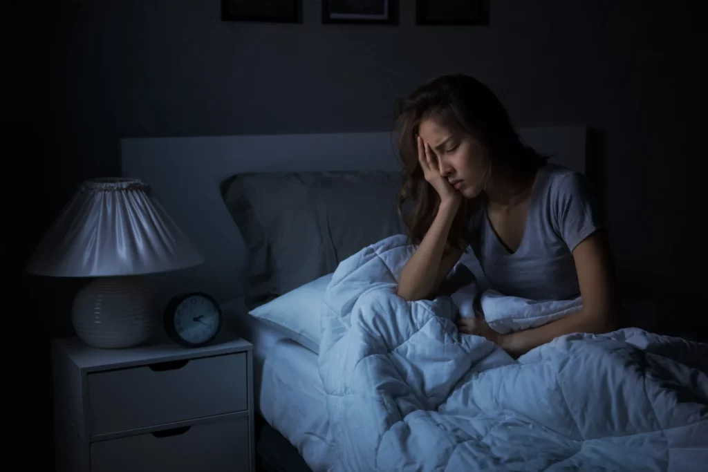 Donna seduta a letto che soffre di insonnia a causa dello stress