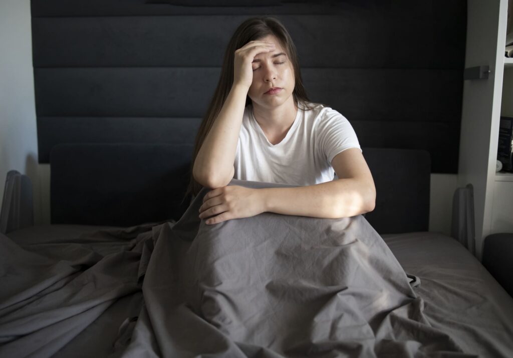 Giovane donna stesa a letto con problemi di insonnia.