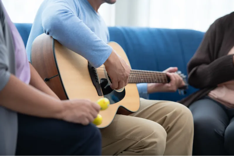 Uomo che suona la chitarra in compagnia degli amici sul divano