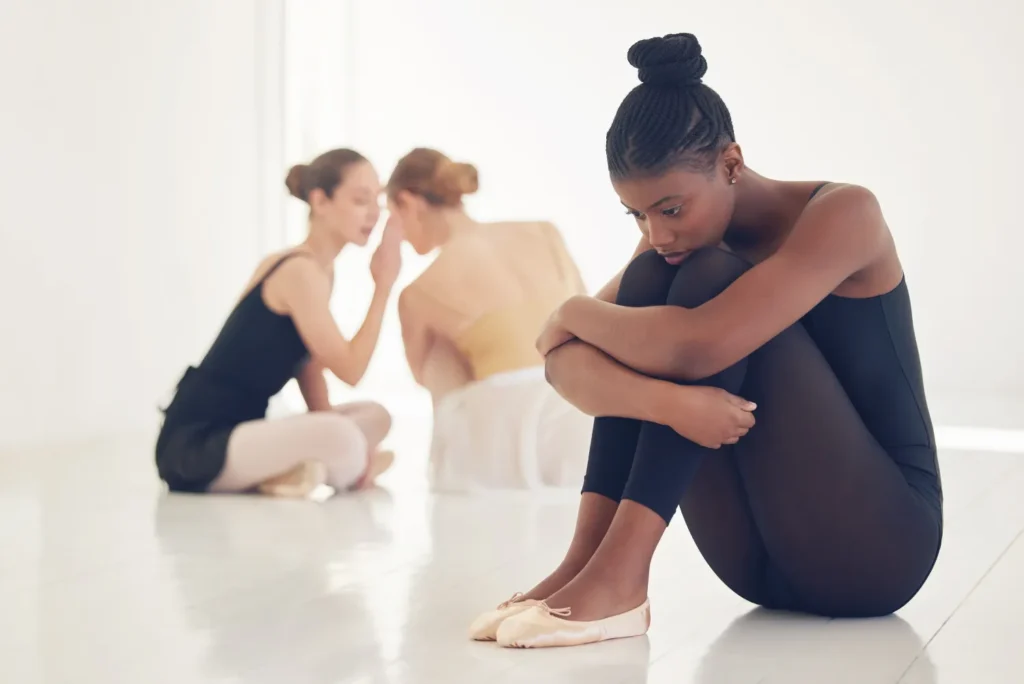 Ragazza triste vestita da ballerina isolata dalle compagne di danza