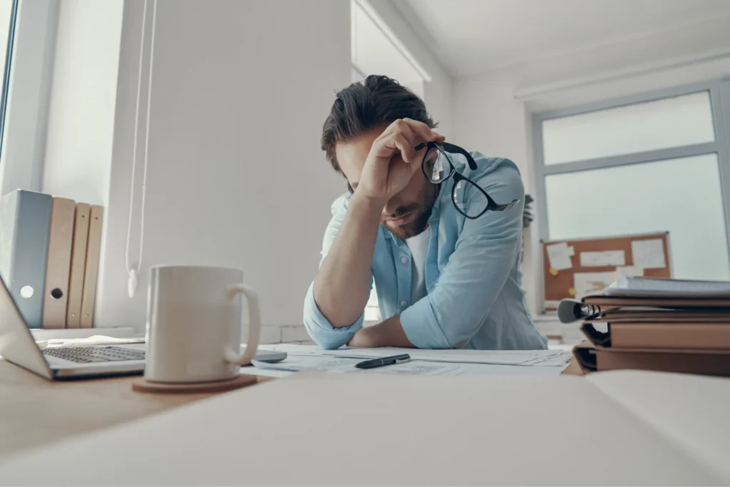 Giovane lavoratore stressato che si appoggia alla scrivania