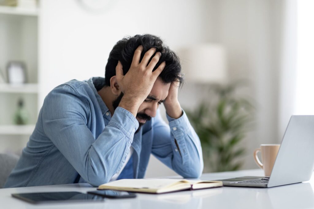Giovane uomo in stato di forte stress per il lavoro in ufficio.