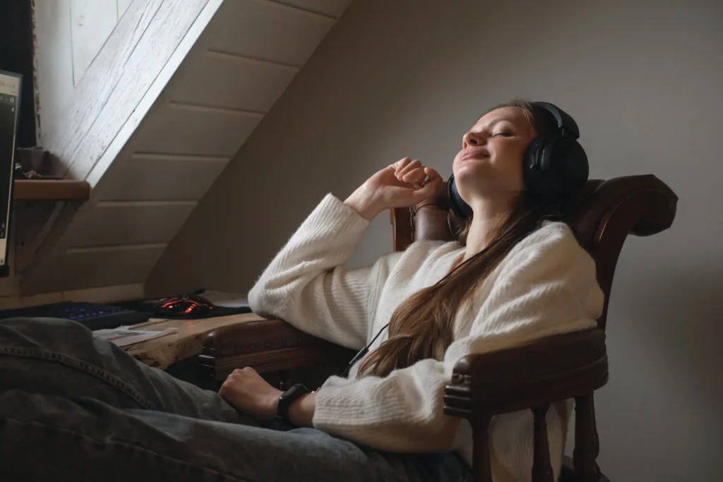 Giovane donna che si rilassa alla scrivania ascoltando musica