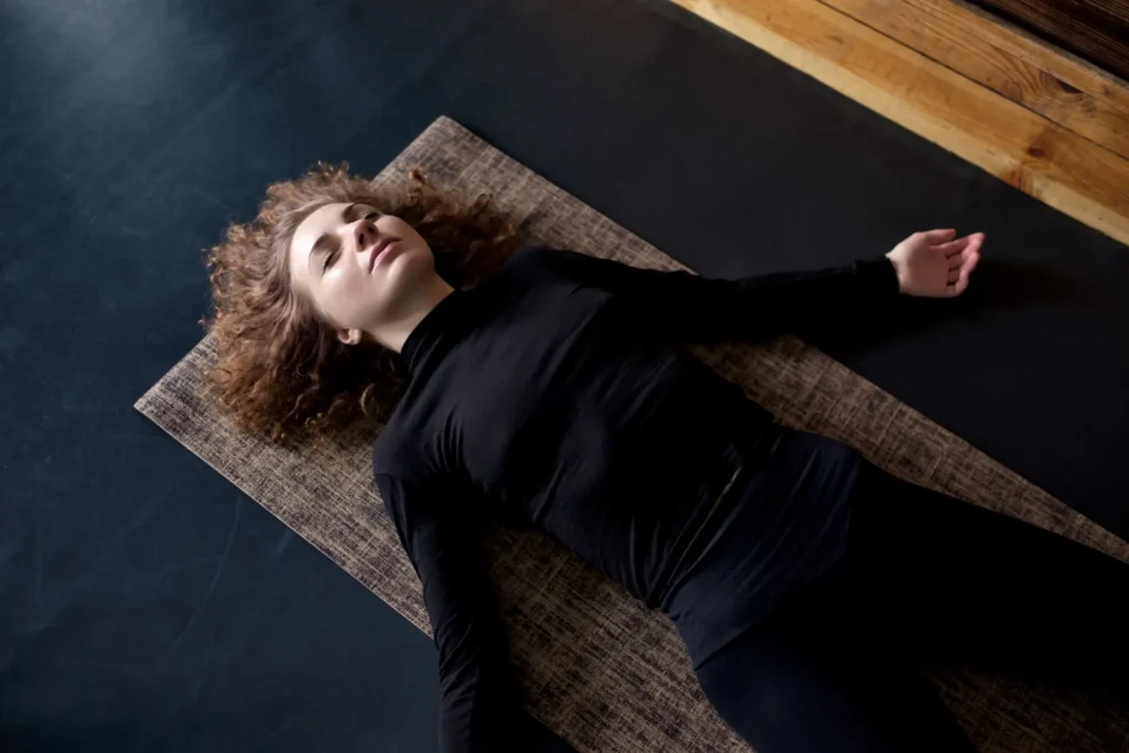 Giovane ragazza stesa sul pavimento mentre pratica body scan