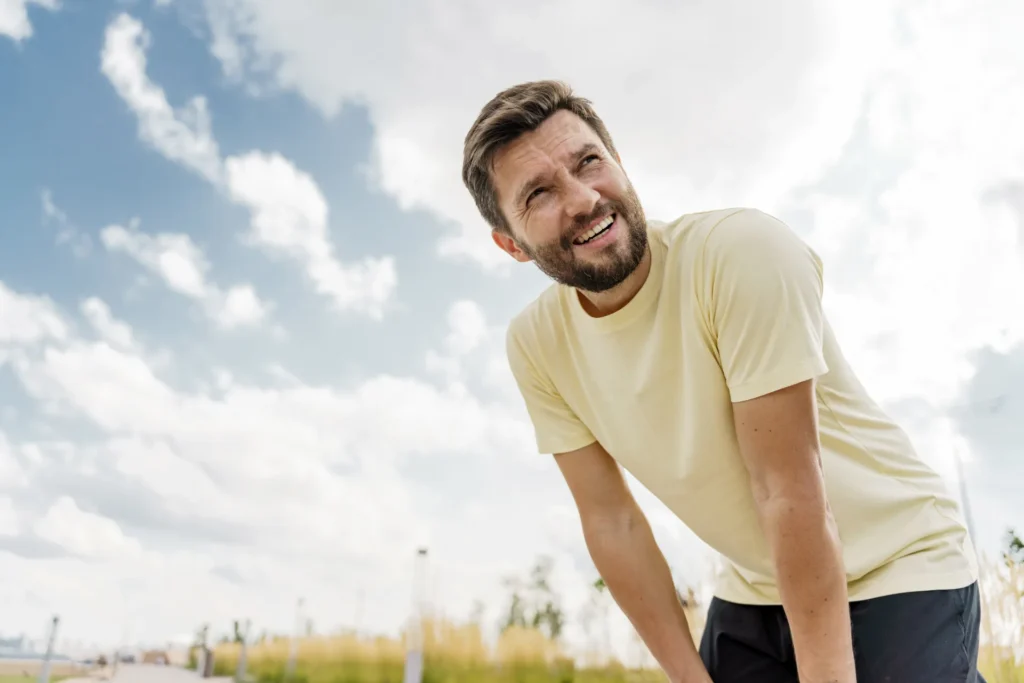 Atleta si riposa con le mani appoggiate sulle ginocchia dopo un allenamento all'aperto