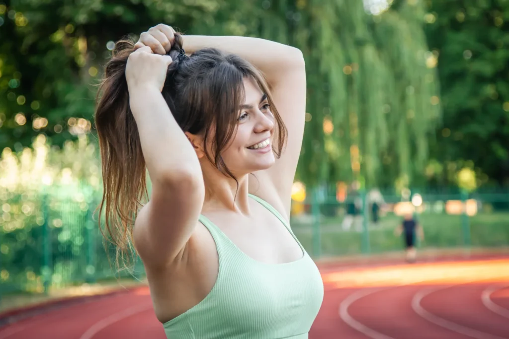 Giovane sportiva sorride mentre si lega i capelli prima di una corsa